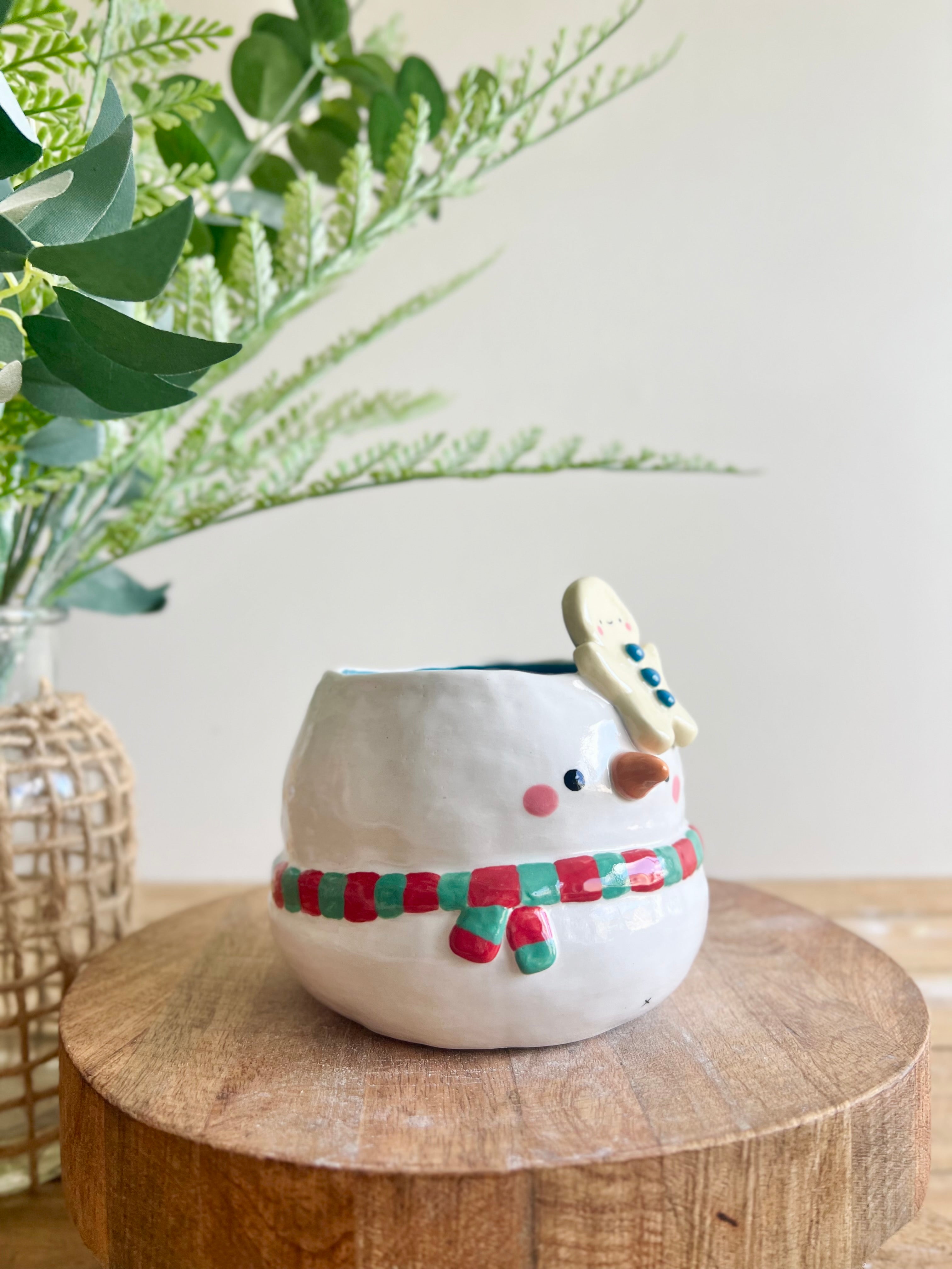 Festive snowman pot with gingerbread friend just chillin’ on its head