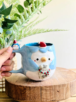 Festive Penguin mug with baby penguin and cat friend