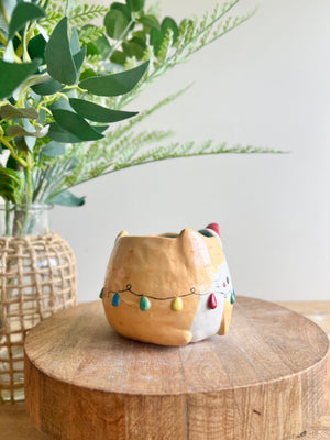 Festive ginger cat pot adorned with Christmas lights