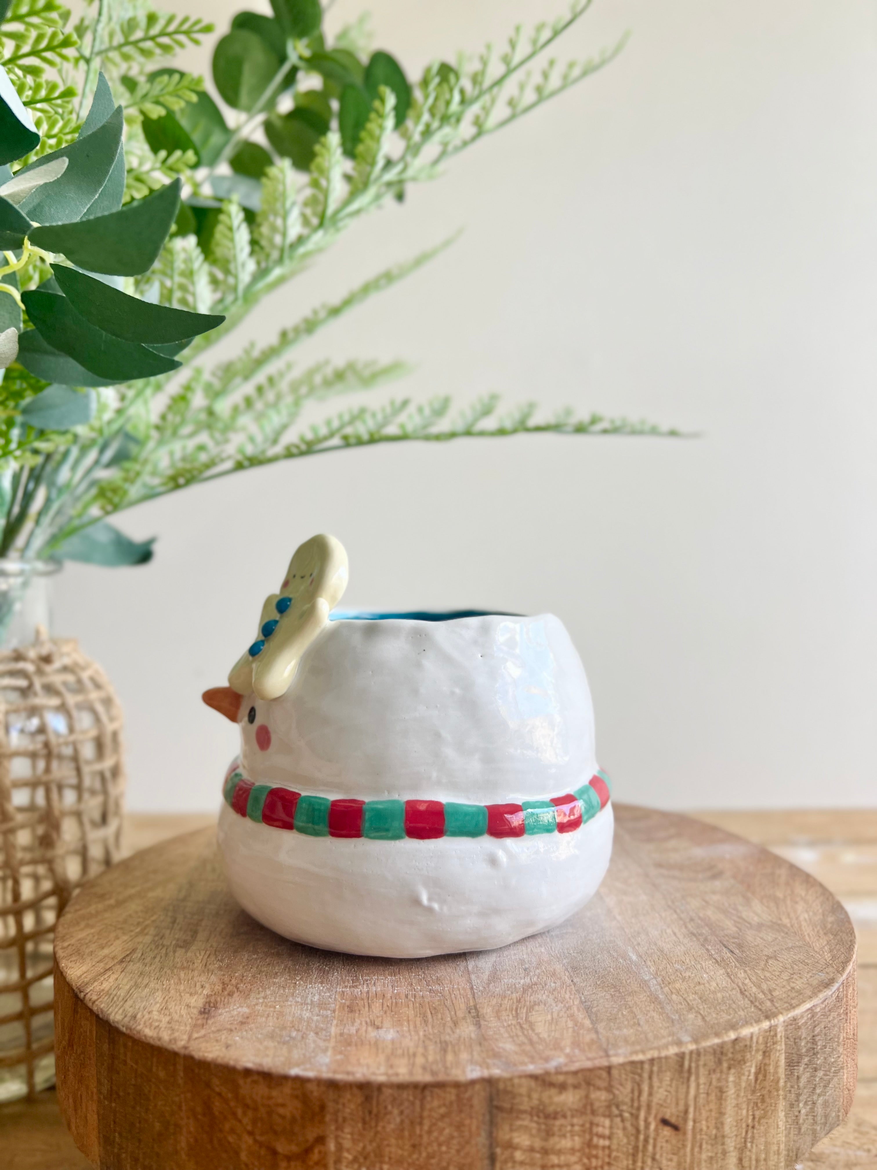 Festive snowman pot with gingerbread friend just chillin’ on its head