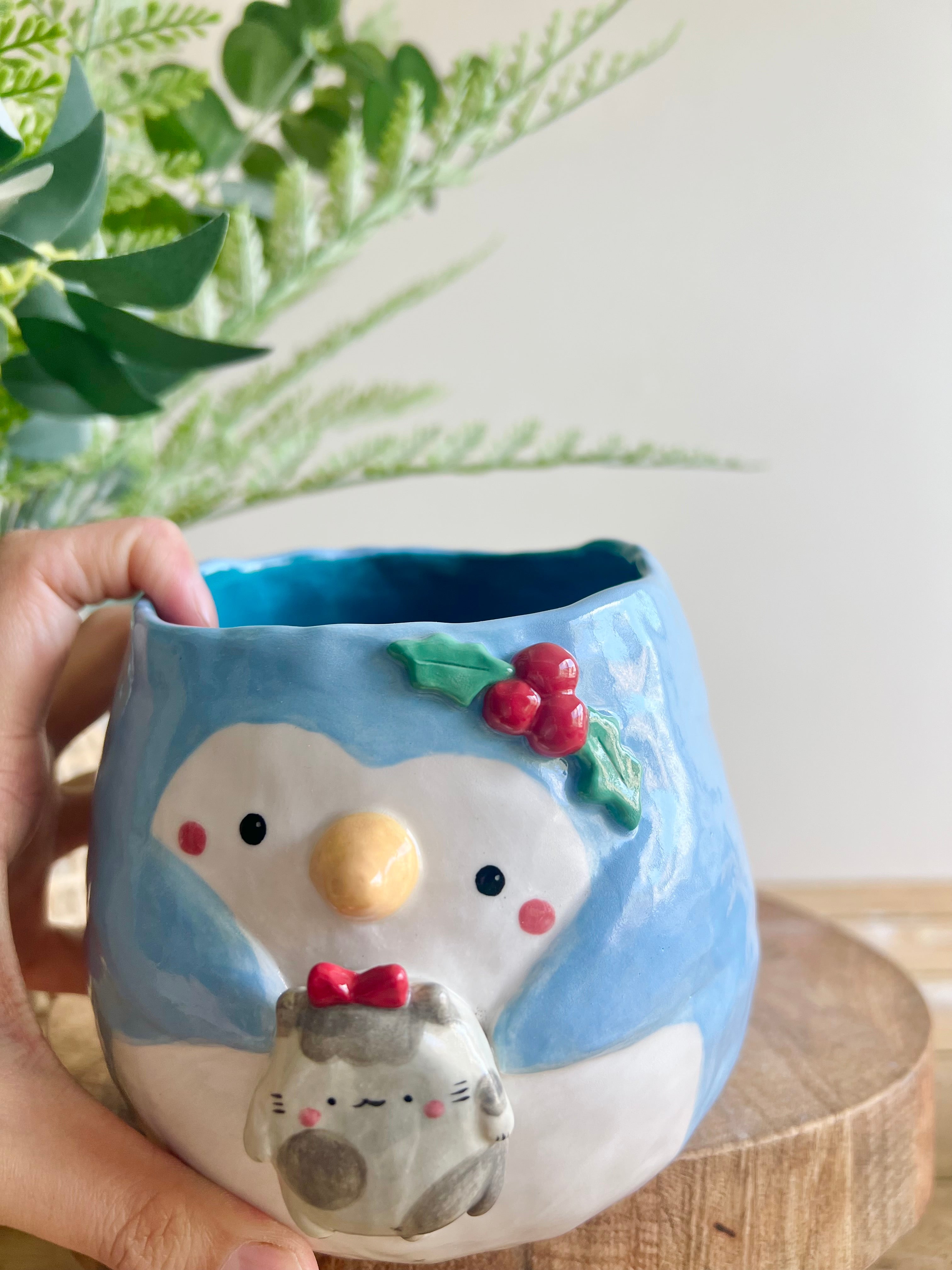 Festive penguin pot with grey cat friend