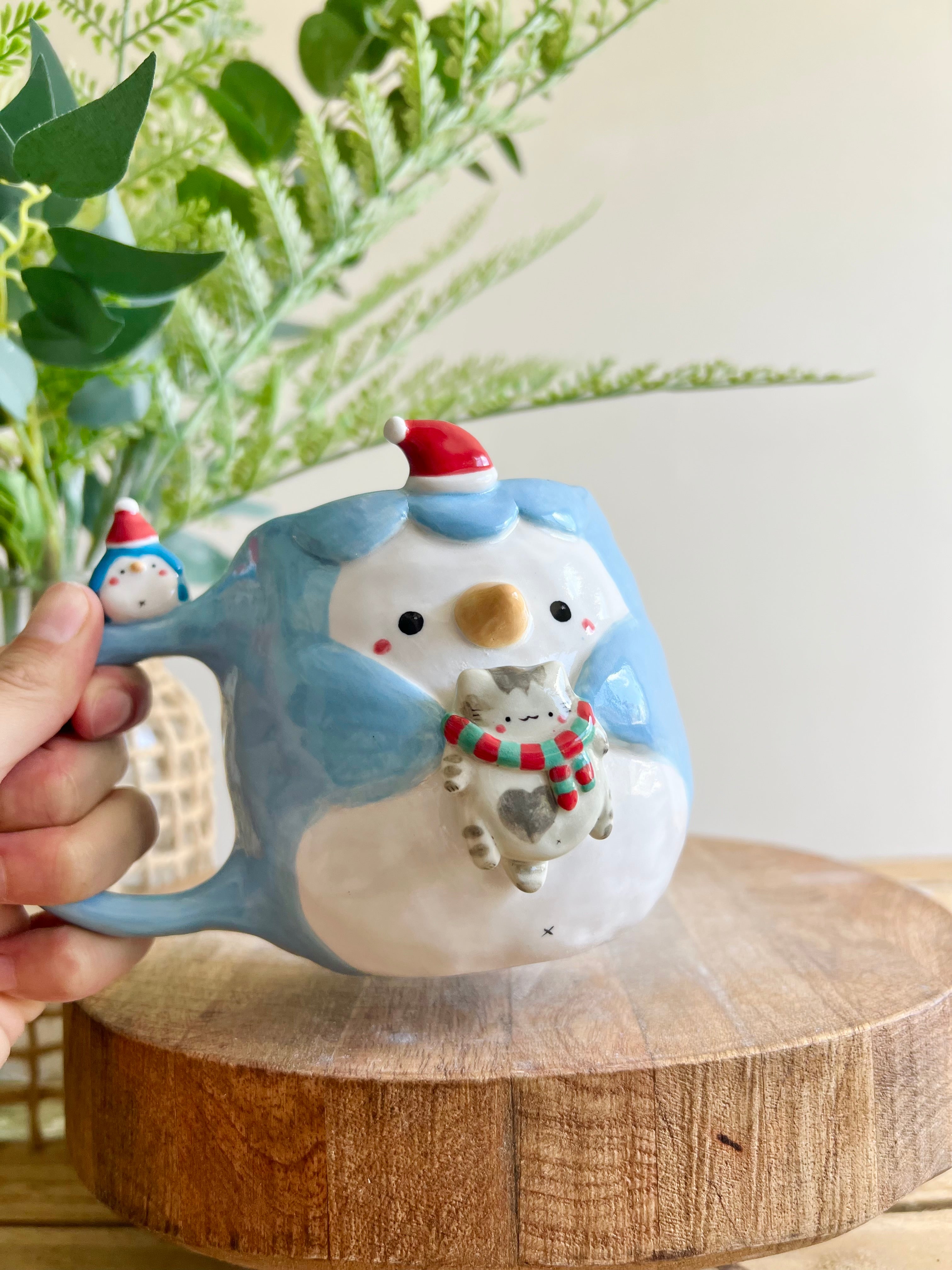 Festive Penguin mug with baby penguin and cat friend