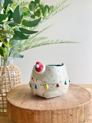 Festive grey cat pot adorned with Christmas lights