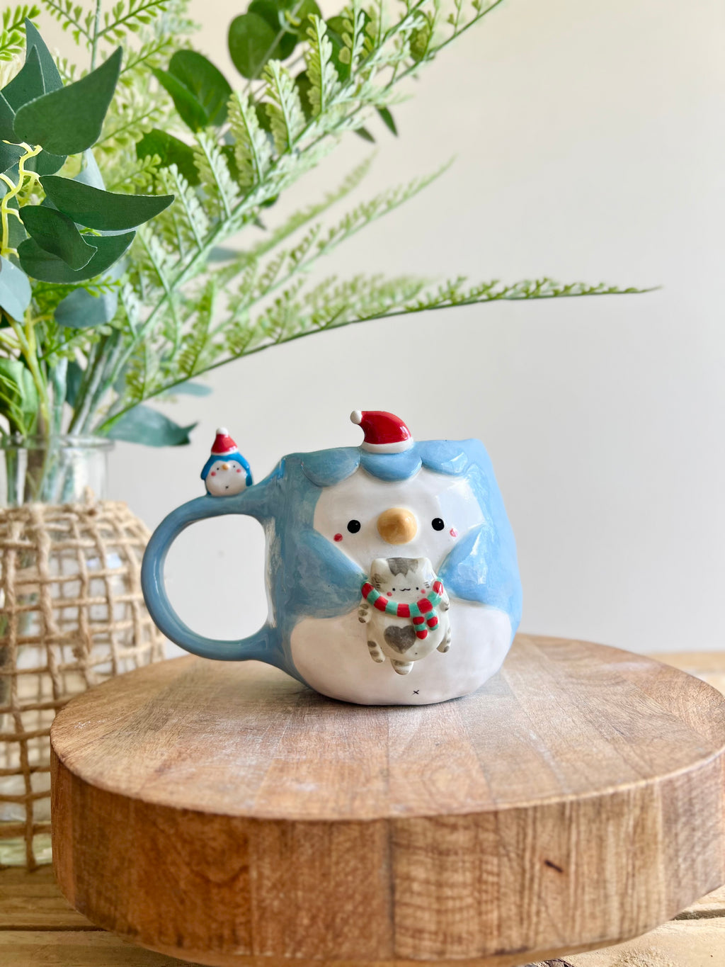 Festive Penguin mug with baby penguin and cat friend