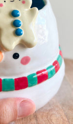 Festive snowman pot with gingerbread friend just chillin’ on its head