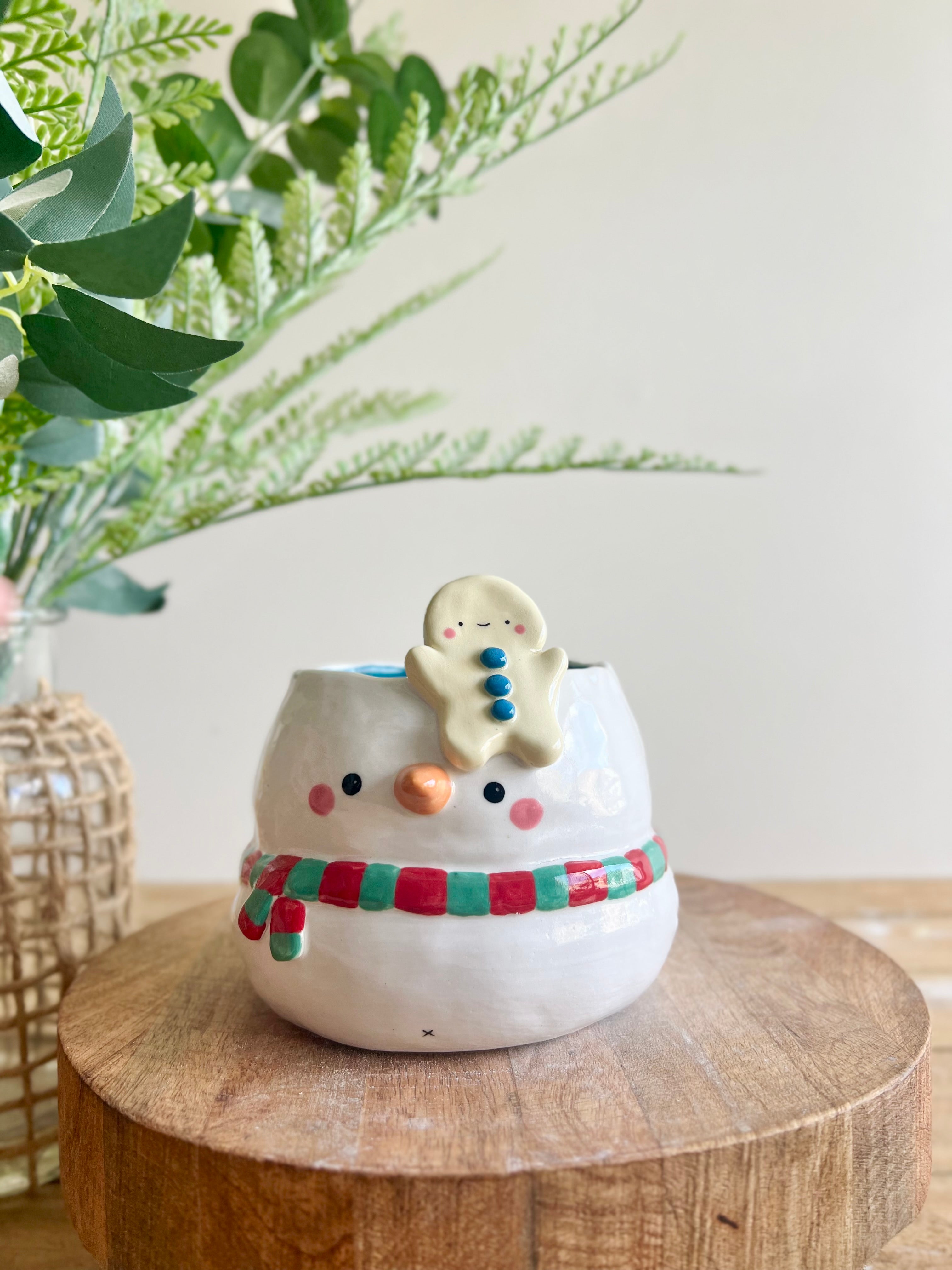 Festive snowman pot with gingerbread friend just chillin’ on its head