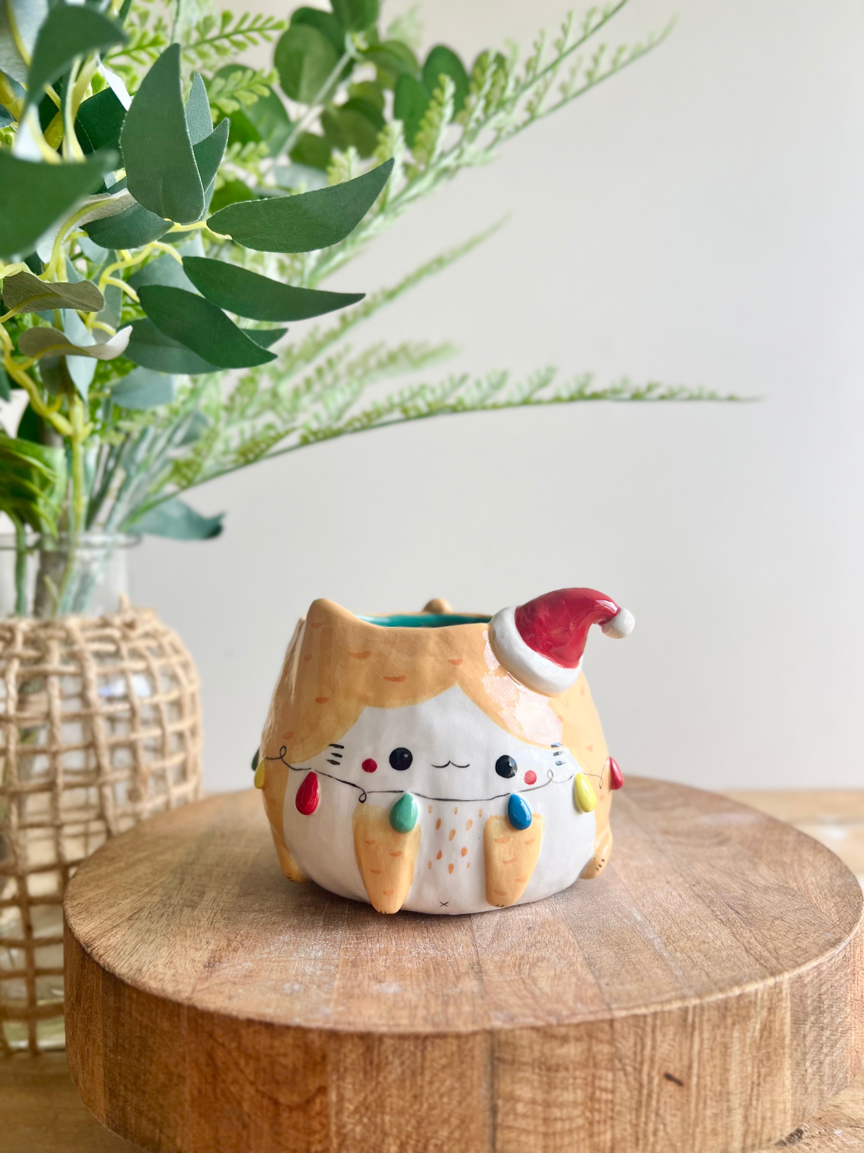 Festive ginger cat pot adorned with Christmas lights