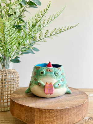 Festive grumpy Froggo planter bearing gift