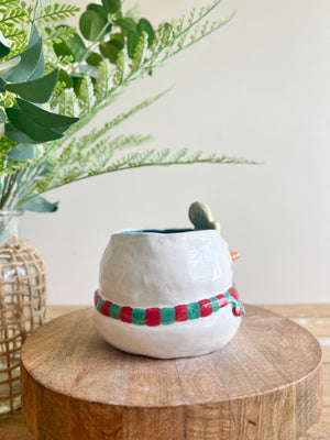 Festive snowman pot with gingerbread friend just chillin’ on its head