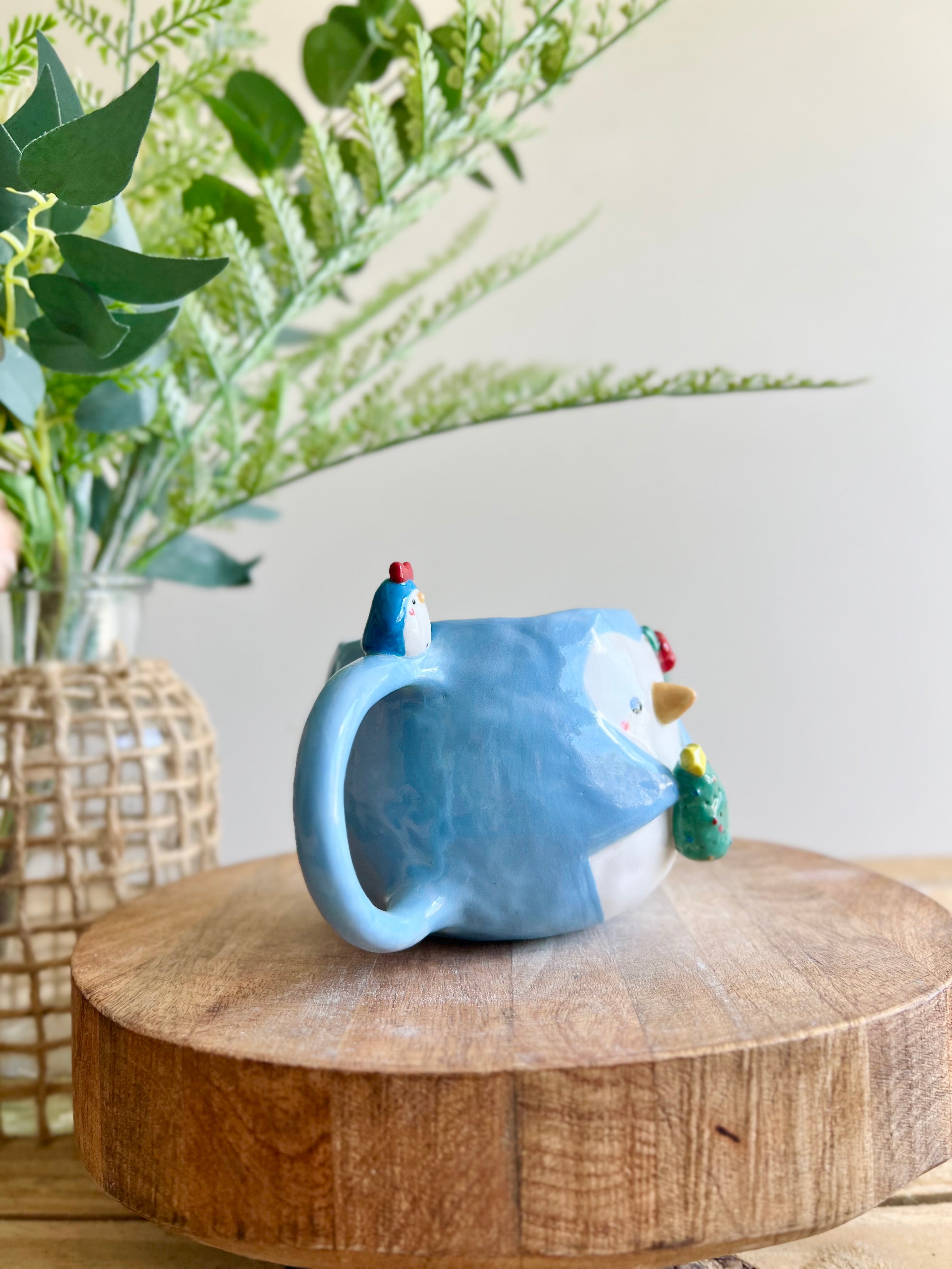 Festive Penguin mug with penguin baby and Christmas tree friend