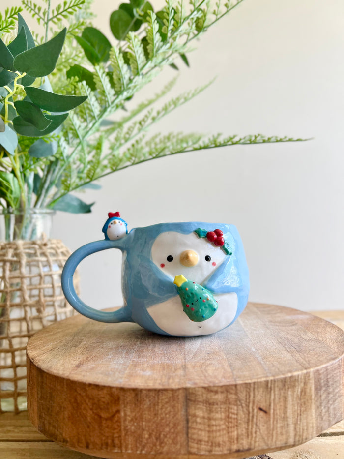 Festive Penguin mug with penguin baby and Christmas tree friend