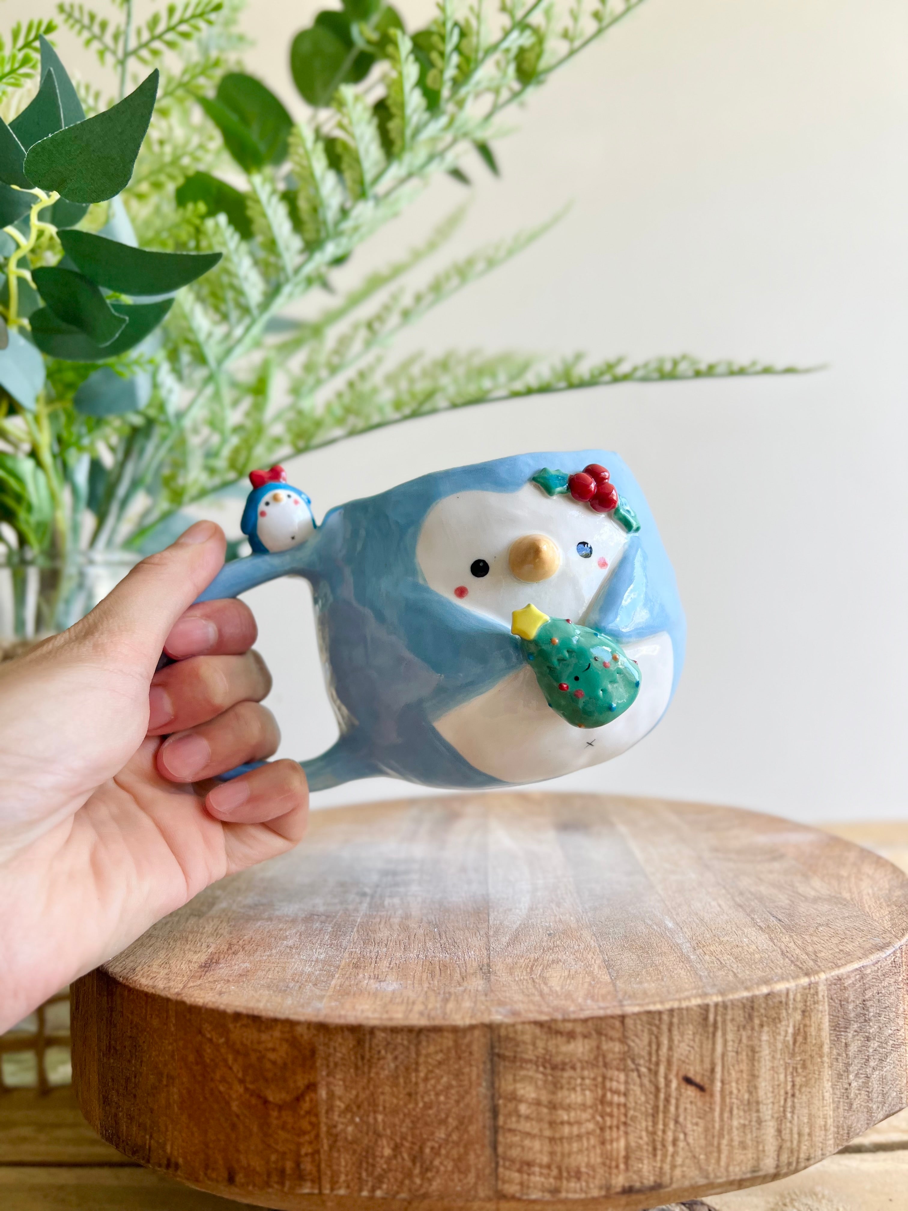 Festive Penguin mug with penguin baby and Christmas tree friend