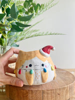 Festive ginger cat pot adorned with Christmas lights