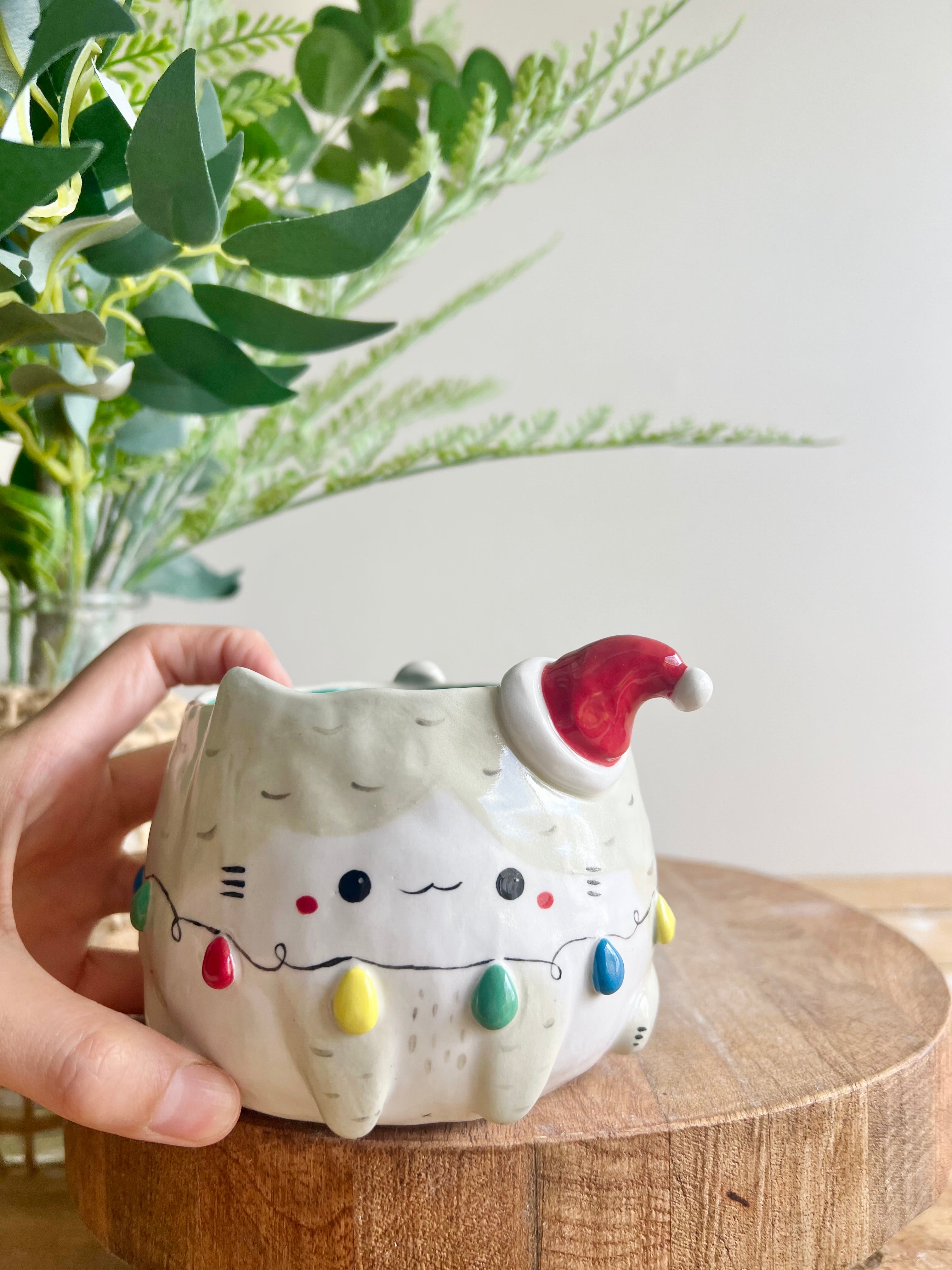 Festive grey cat pot adorned with Christmas lights