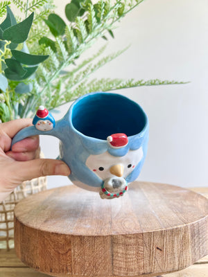 Festive Penguin mug with baby penguin and cat friend