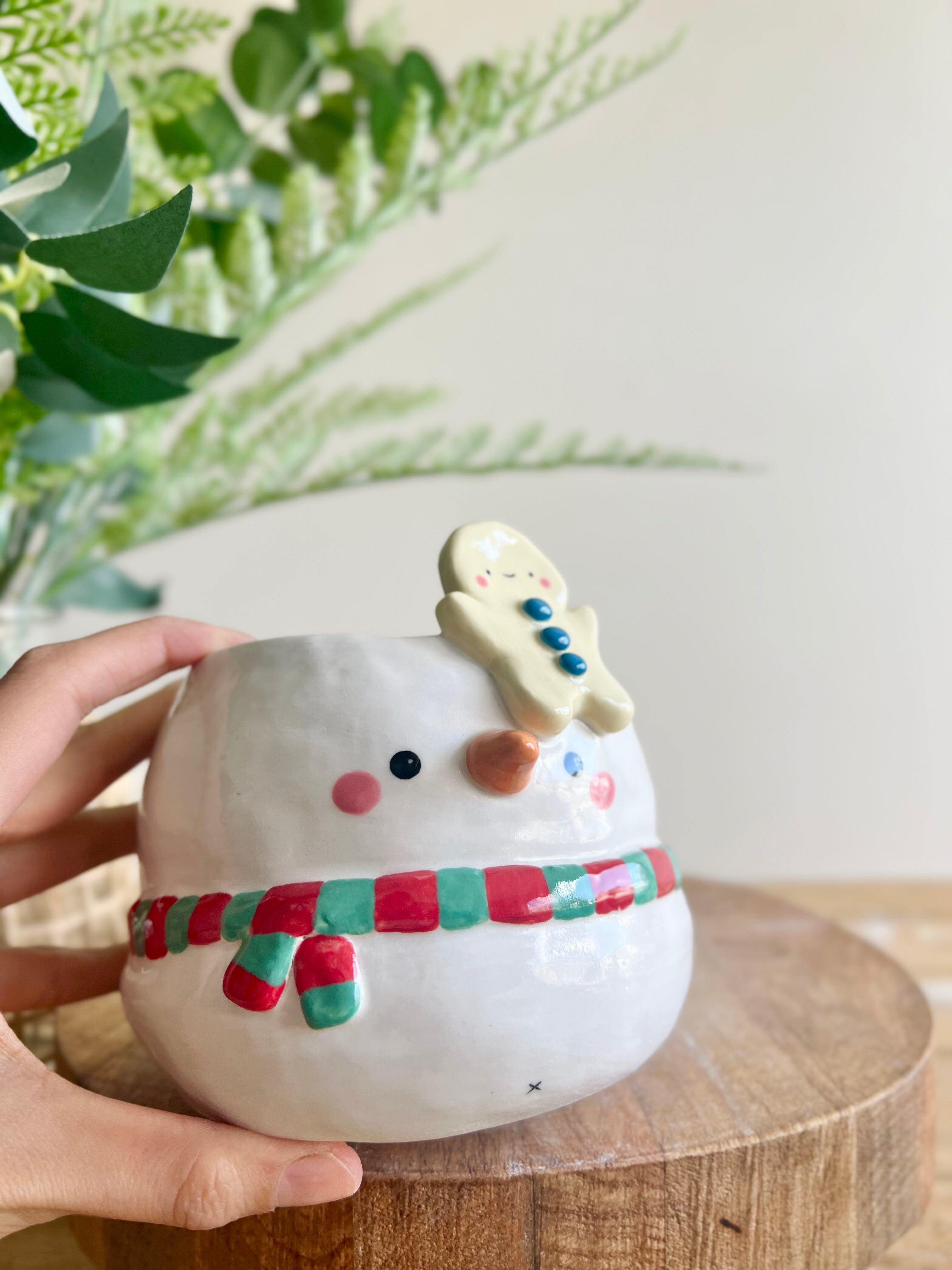 Festive snowman pot with gingerbread friend just chillin’ on its head