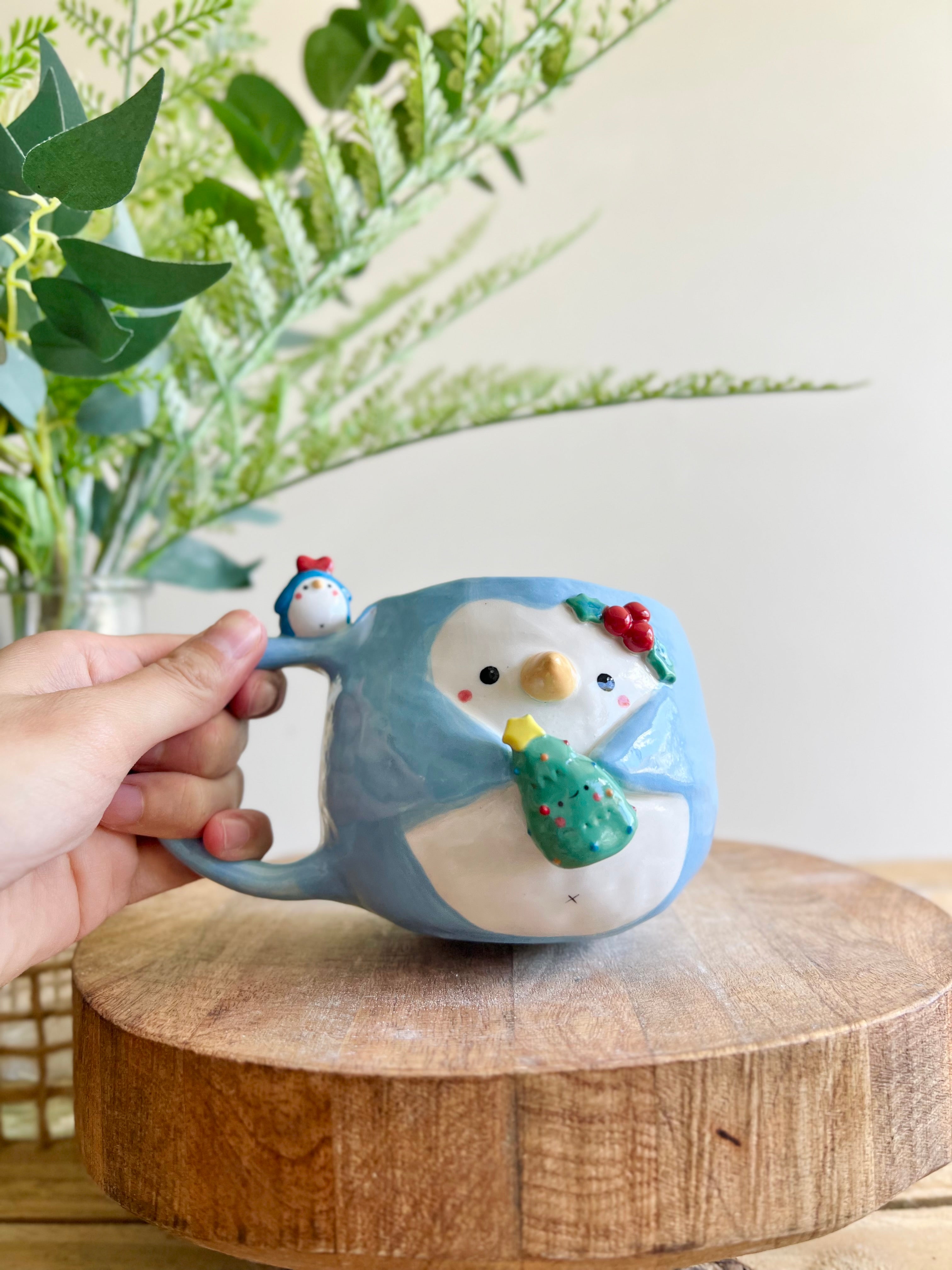 Festive Penguin mug with penguin baby and Christmas tree friend