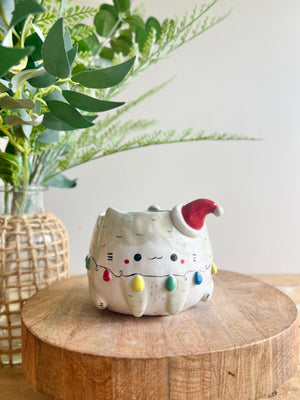 Festive grey cat pot adorned with Christmas lights