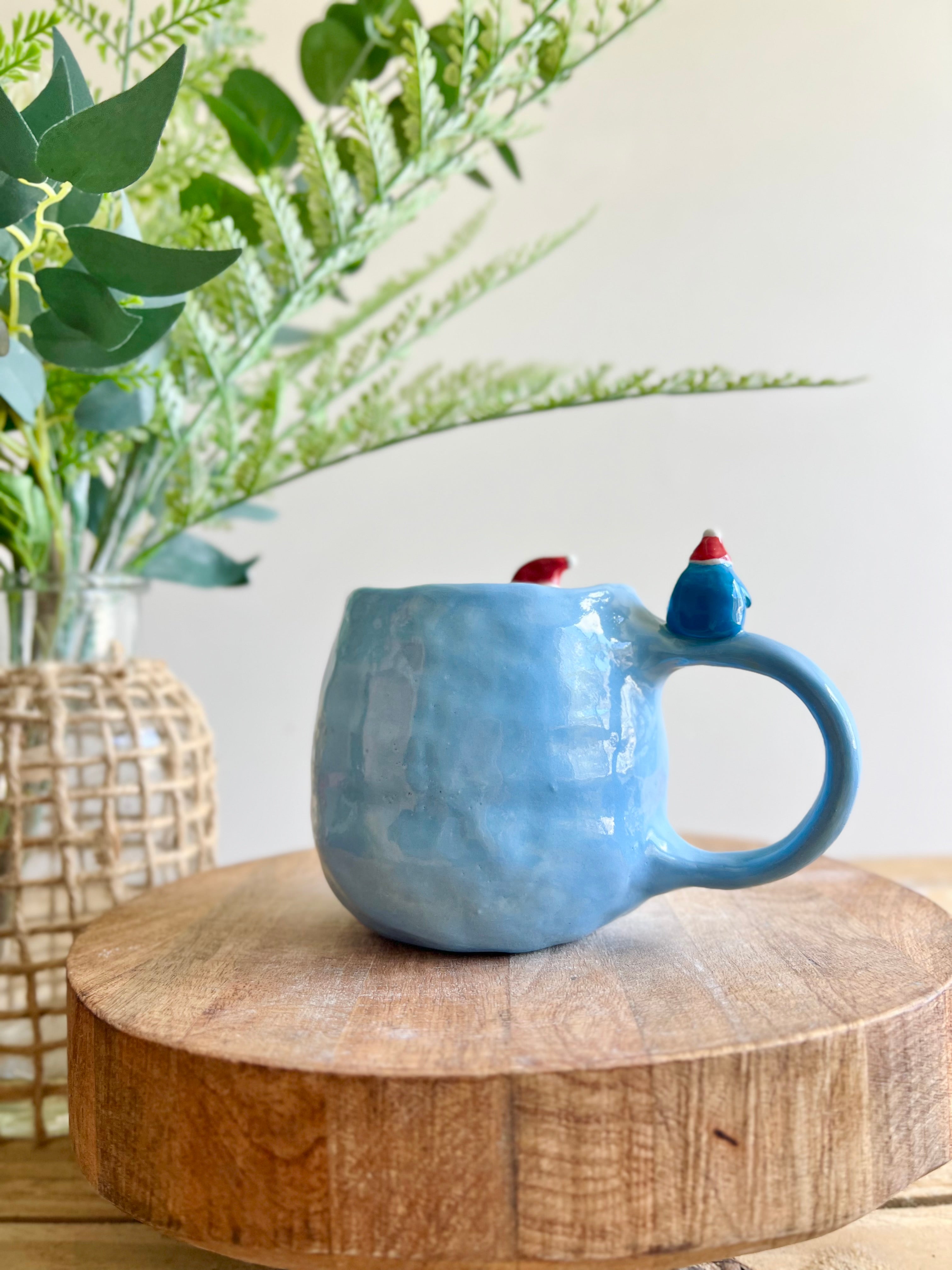 Festive Penguin mug with baby penguin and cat friend