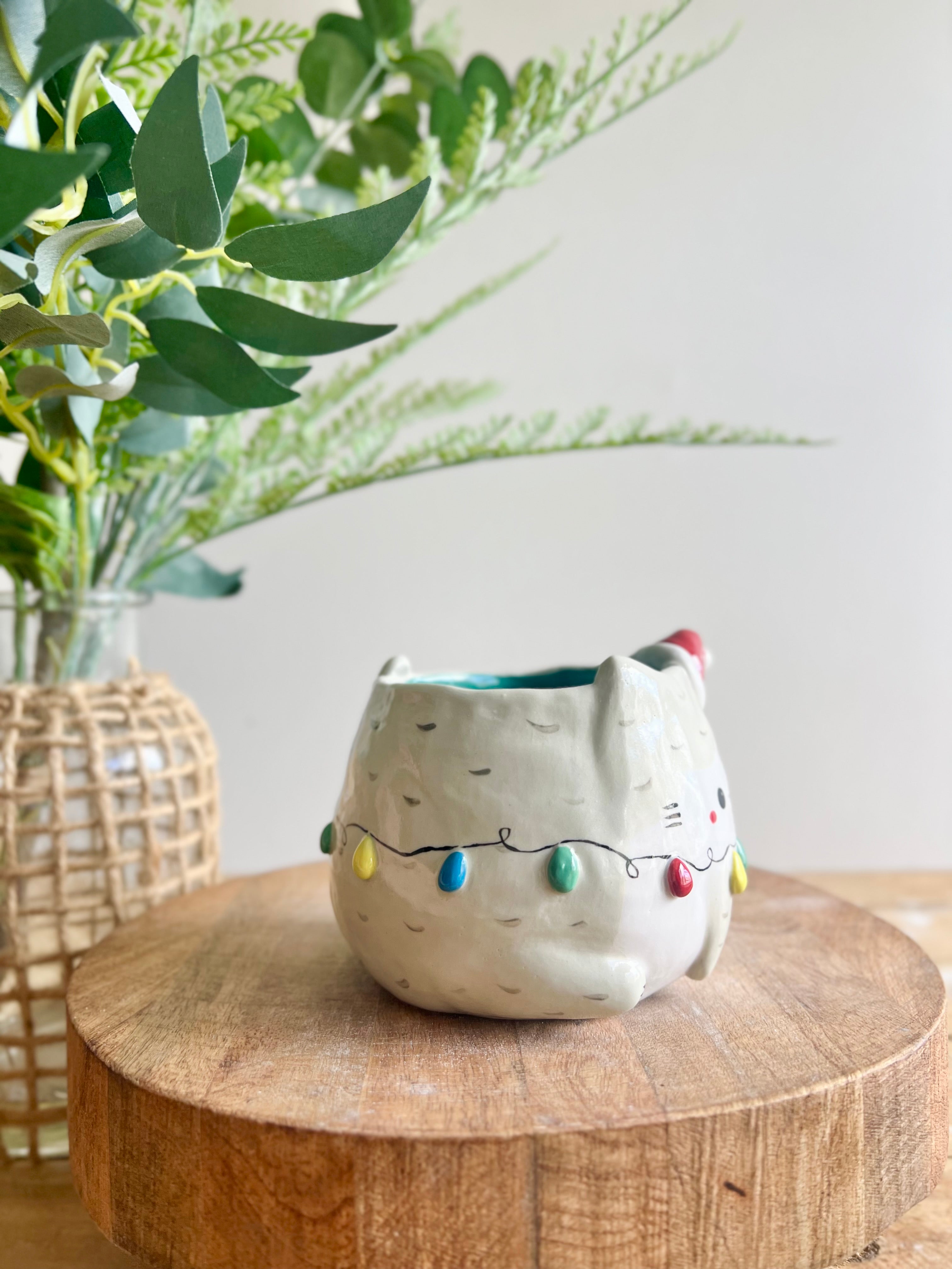 Festive grey cat pot adorned with Christmas lights