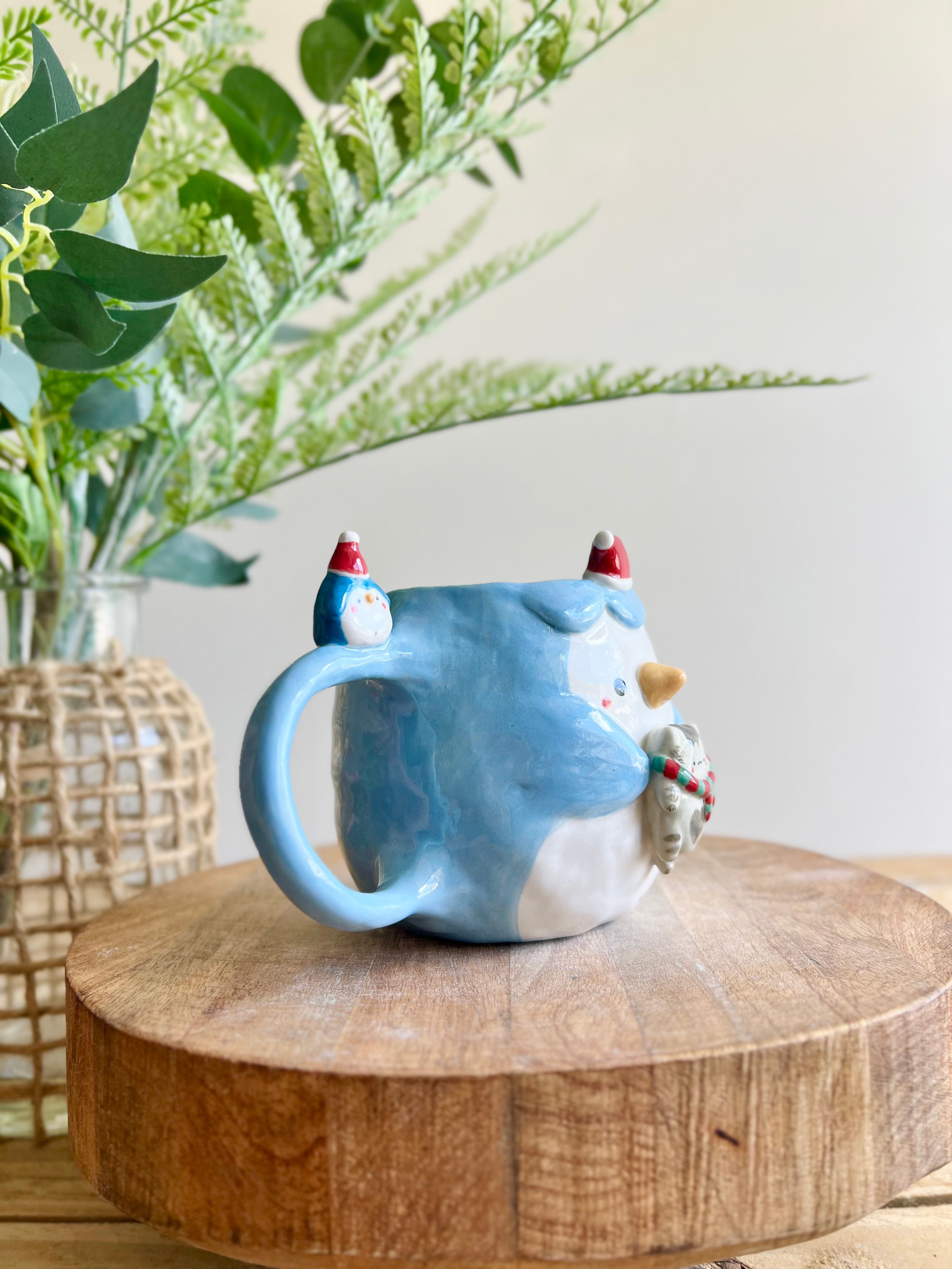 Festive Penguin mug with baby penguin and cat friend