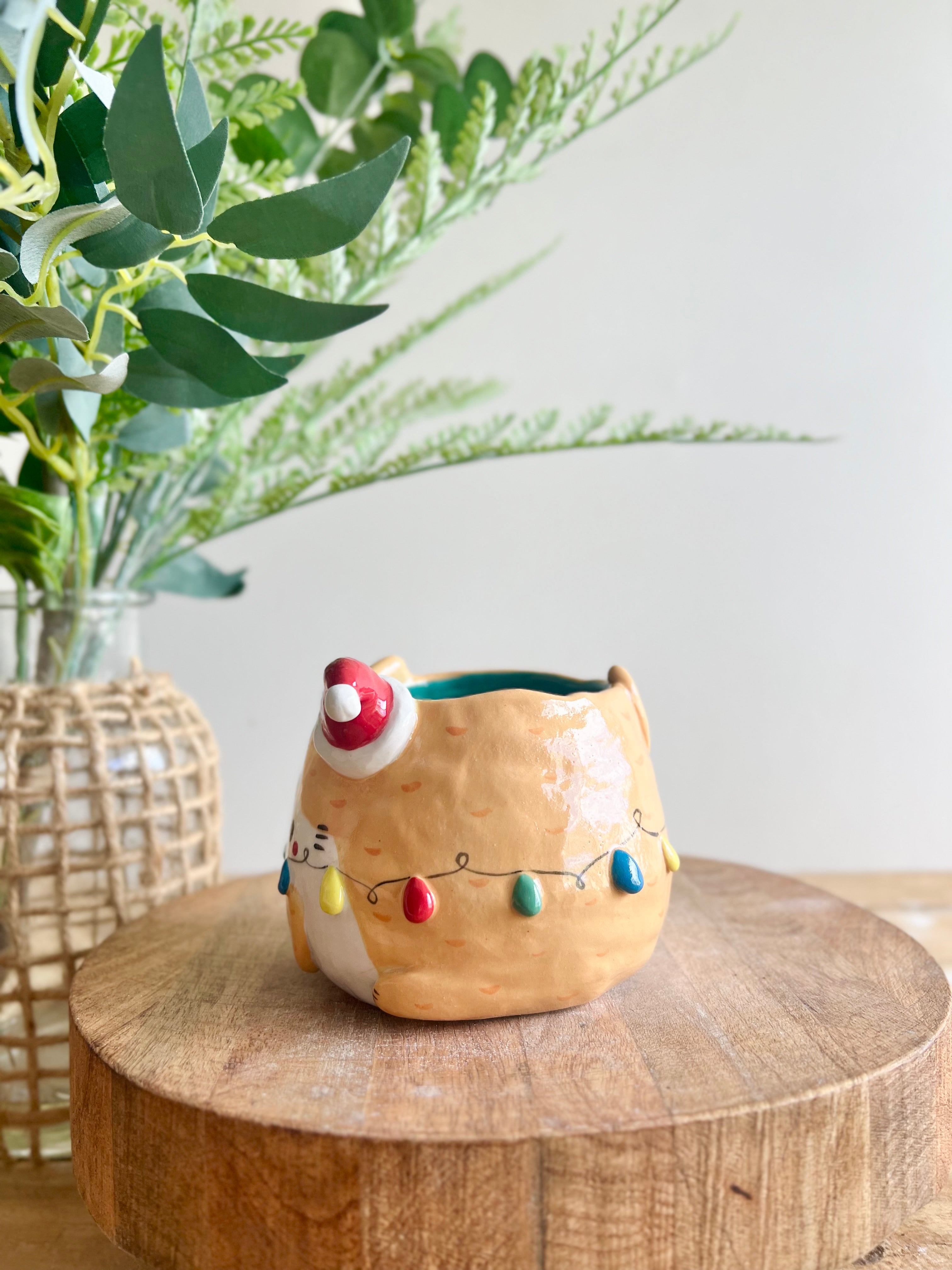 Festive ginger cat pot adorned with Christmas lights