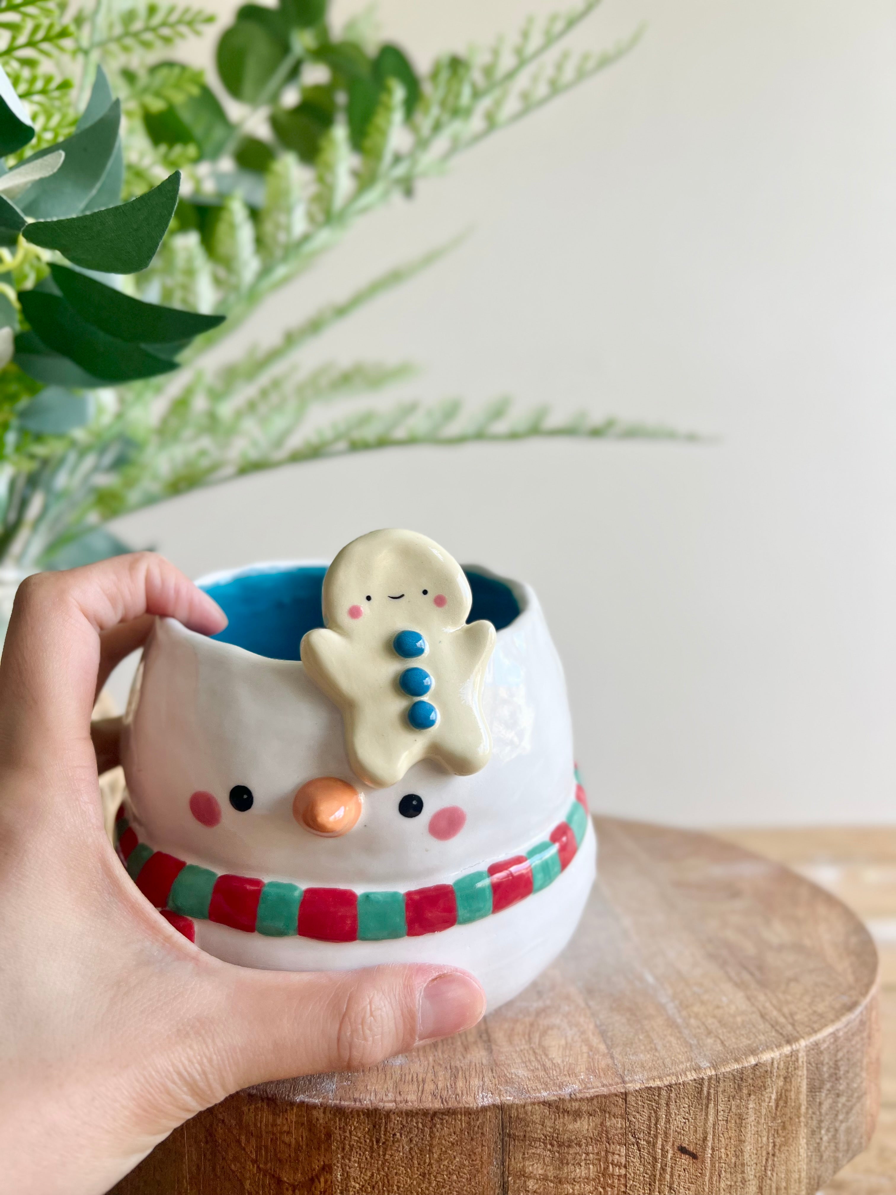 Festive snowman pot with gingerbread friend just chillin’ on its head