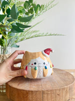 Festive ginger cat pot adorned with Christmas lights