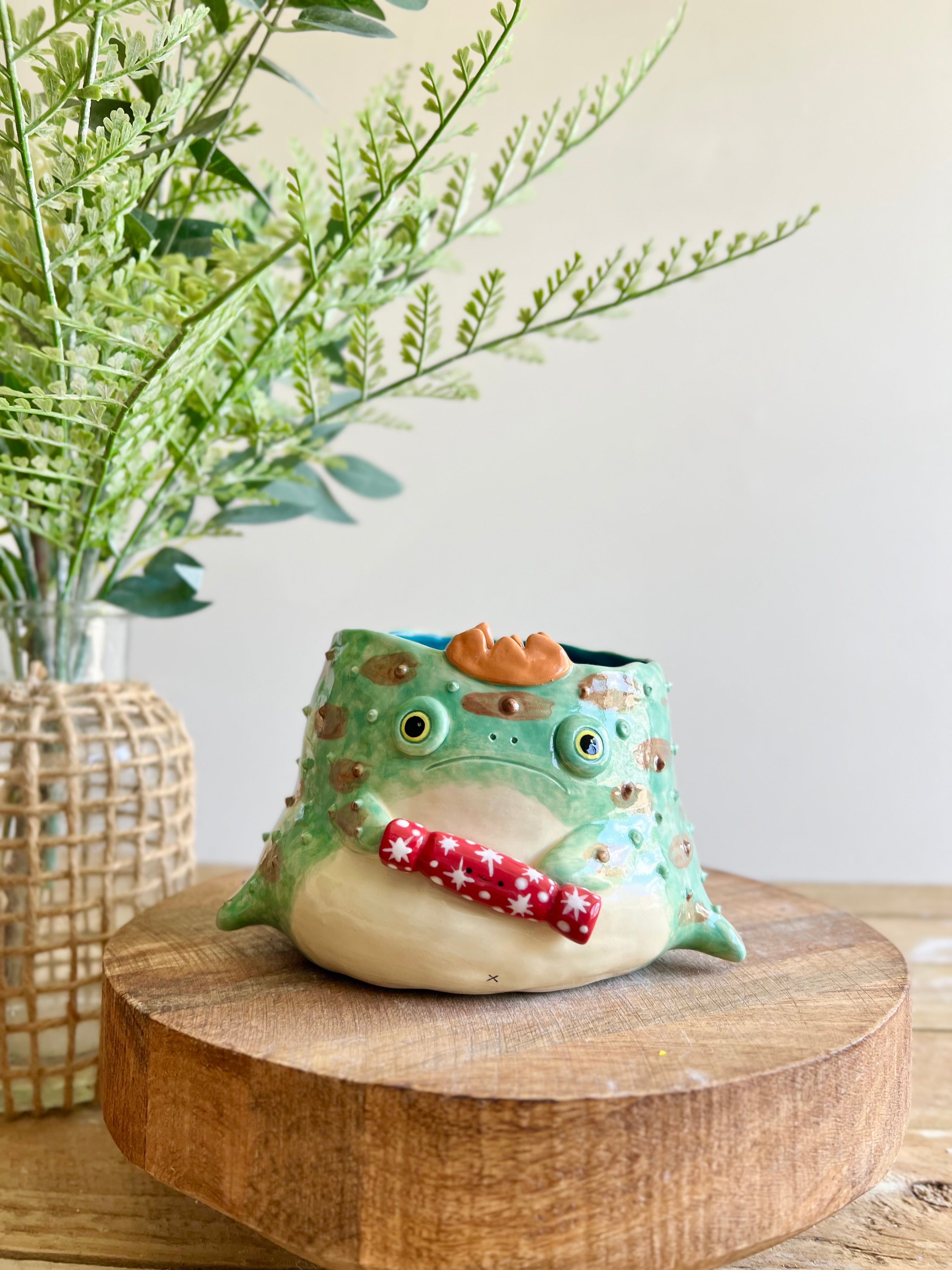 Festive grumpy Froggo planter cracks bon bon with you