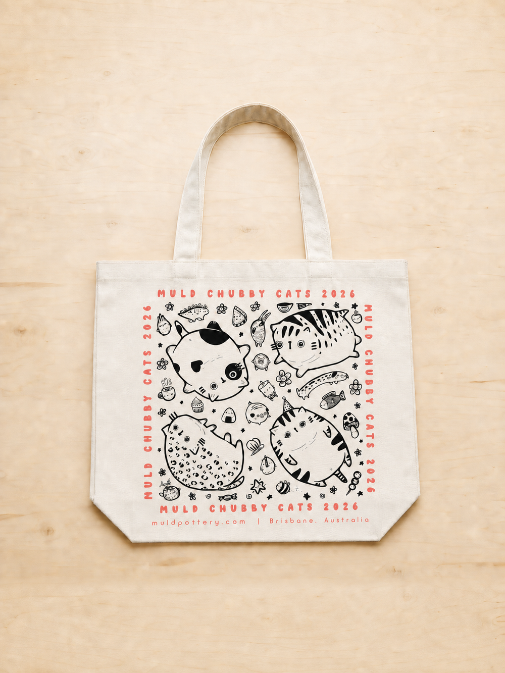 Cream Chubby Cats exhibition tote bag with centred print, portrait flat lay on pale timber