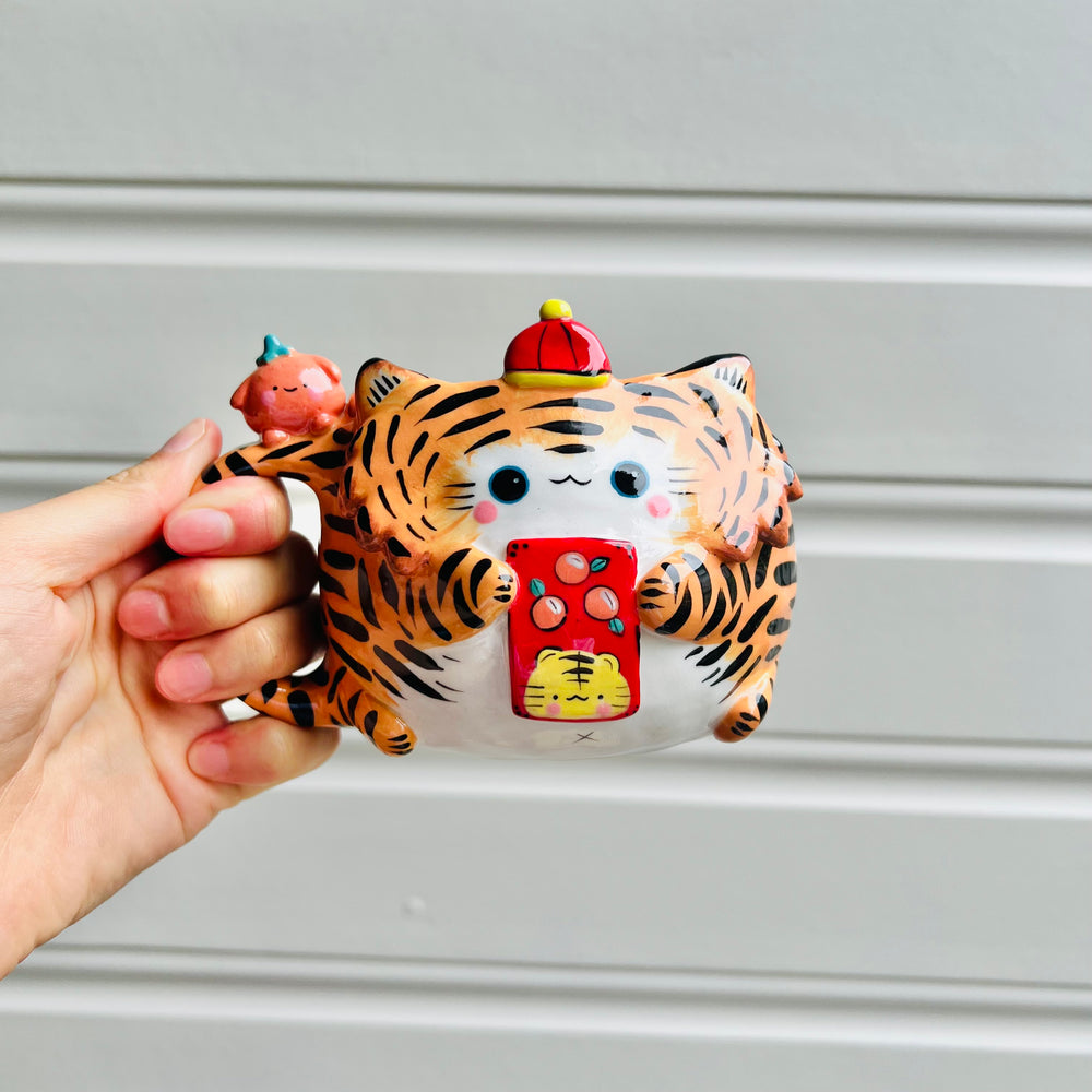 Hat wearing tiger and mandarin friend mug with red packet, photo 1 of 5