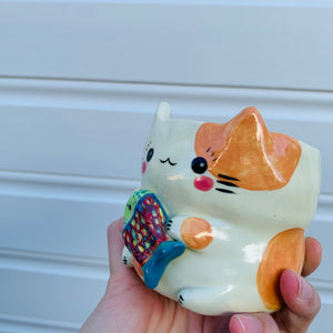 Small spotty cat with fish friend planter