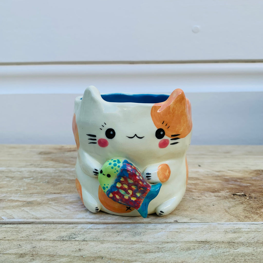 Small spotty cat with fish friend planter