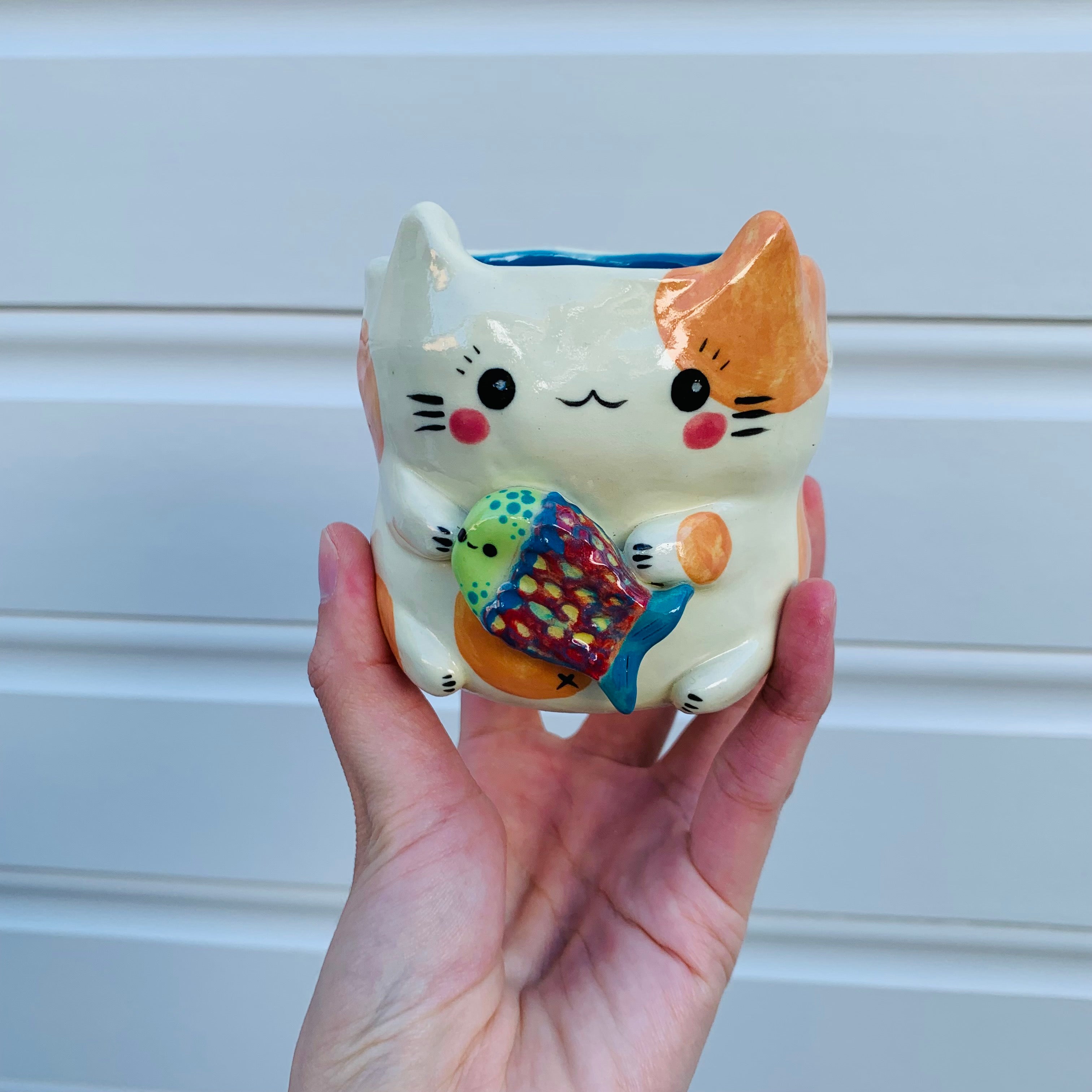 Small spotty cat with fish friend planter